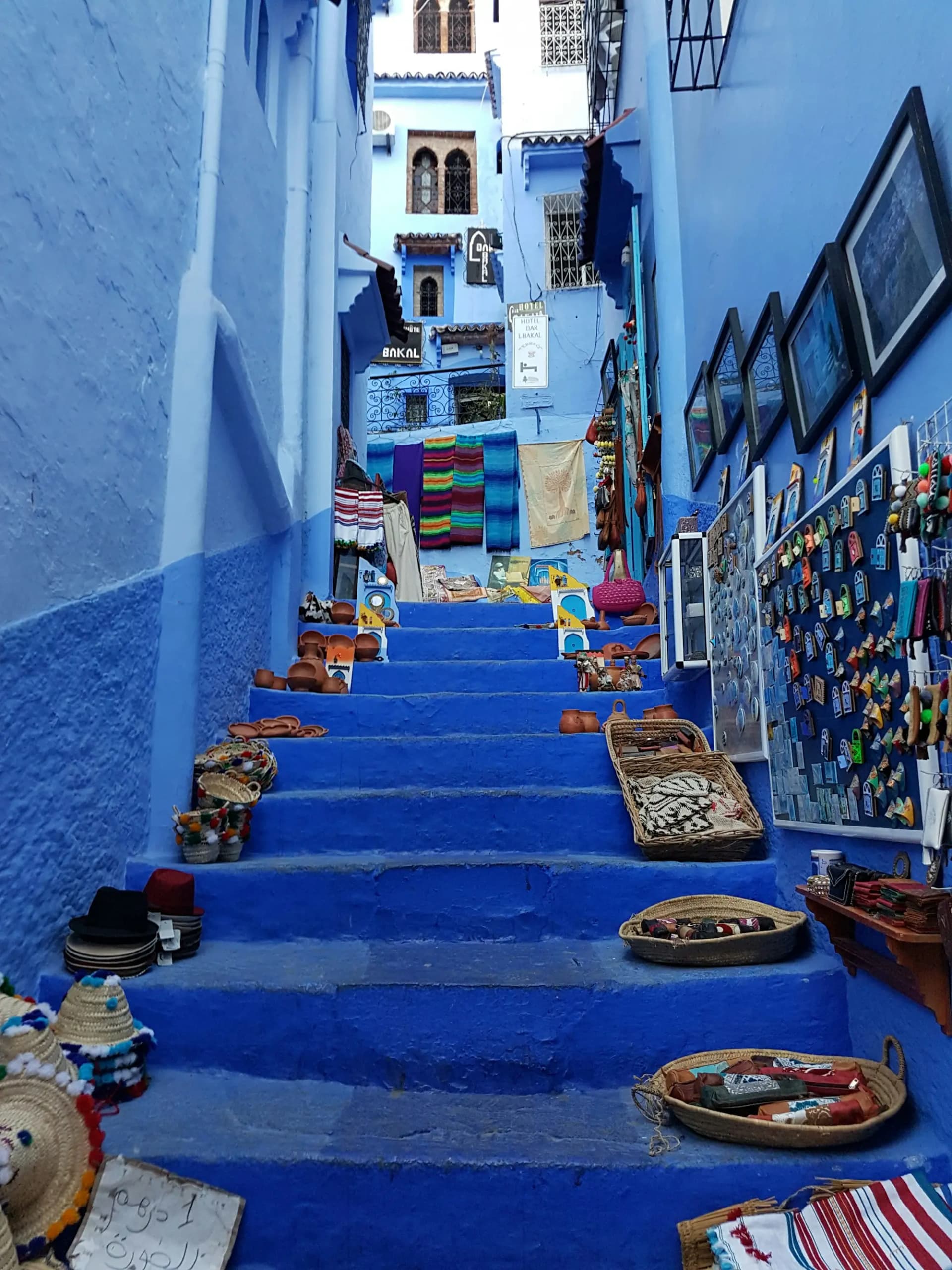 Blue-painted stairs in the Chefchaouen medina lined with baskets and textiles