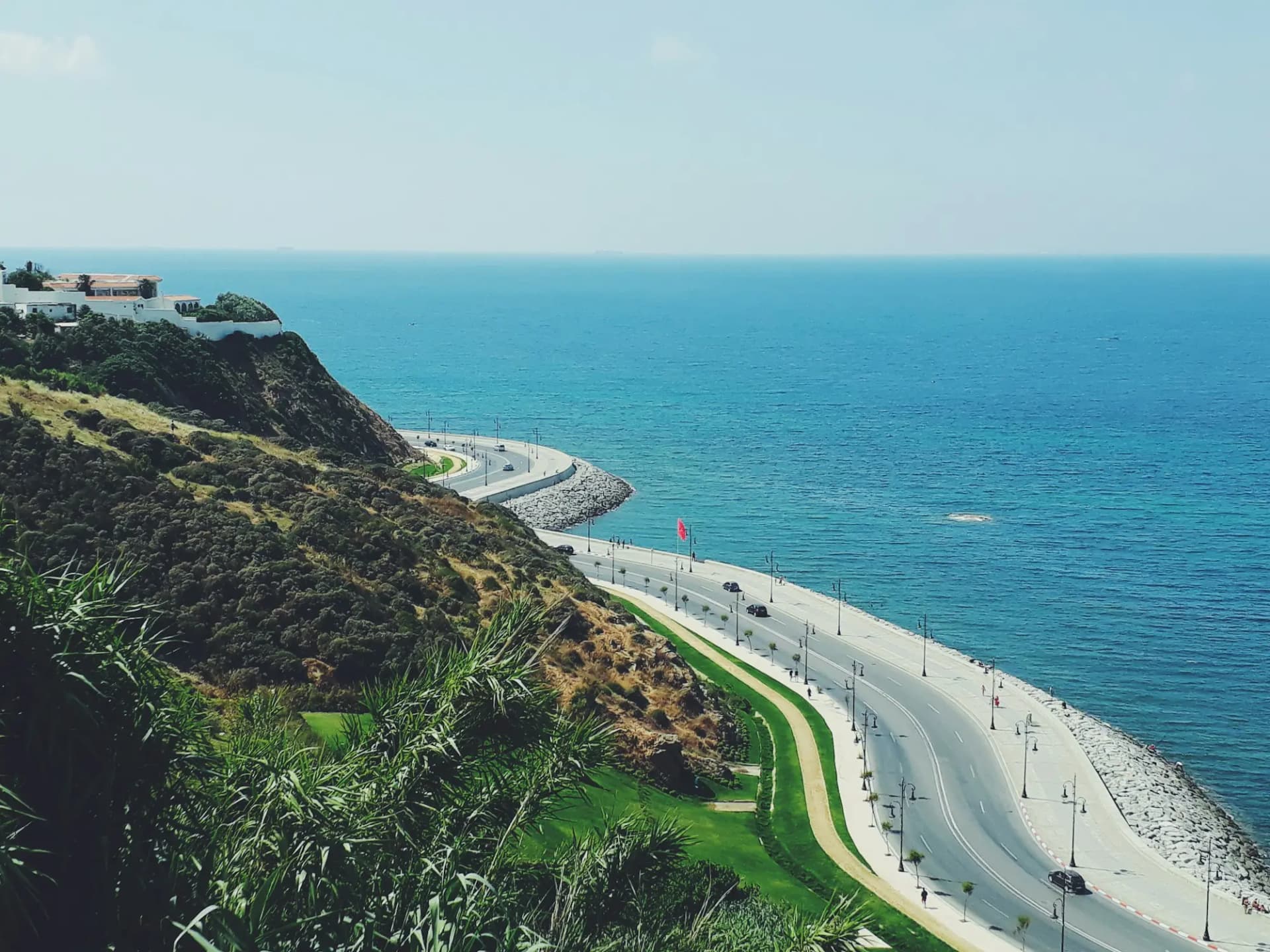 Coastal road curving along green hills above the sea in northern Morocco