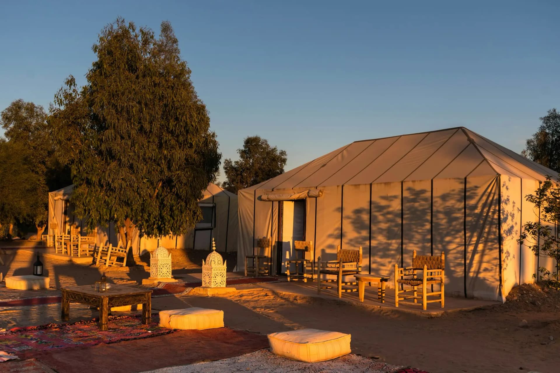 Canvas tent and outdoor seating at a desert camp in warm evening light